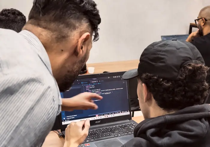 Aula com instrutor ao fundo e monitor ao lado de um aluno